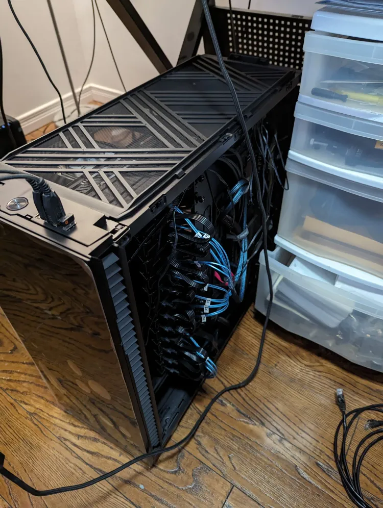 A picture of Core Lab Custom Server/NAS while being built, on a floor beside oragizer bin, with drive cables hanging out and side, top panels removed.