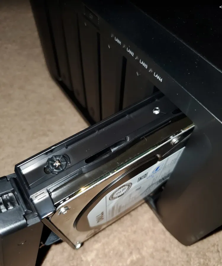 A pre-built NAS being setup with the final (6th) 3.5" HDD sliding into the drive bay.